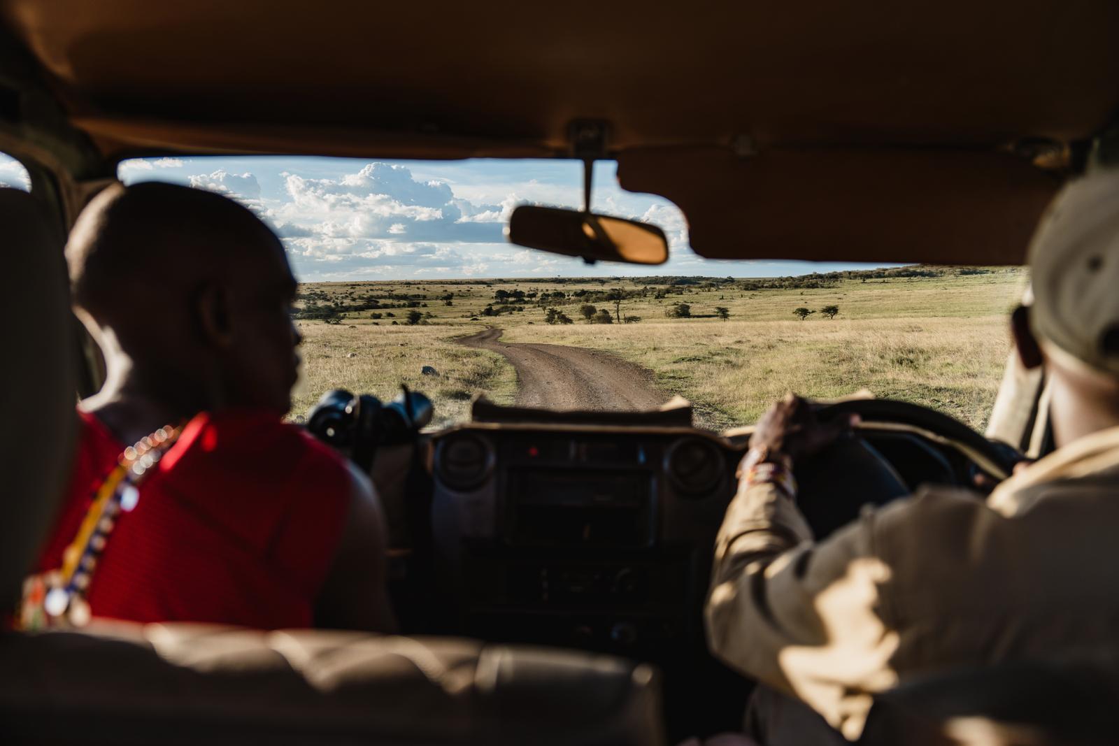 Gidsen in safari-jeep in Kenia kijken uit over de savanne op zoek naar wildlife
