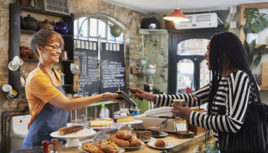 Vrouw betaalt in café voor koffie met haar mobiel