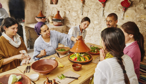 Middelbreed shot van een instructeur die een deksel op een door de studenten gemaakte tajine legt, voordat deze in een houtgestookte oven wordt bereid