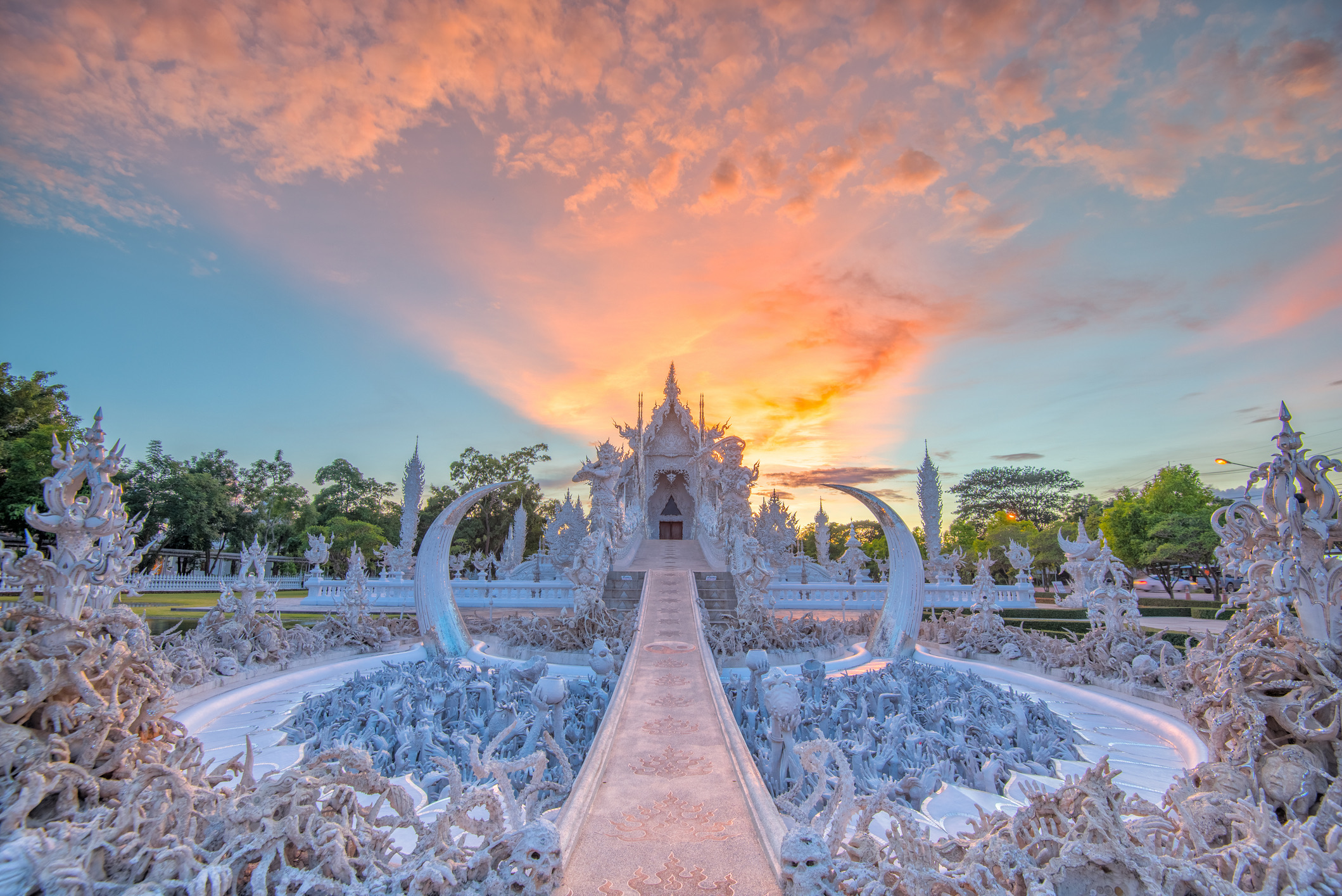 In het noorden van Thailand, vlak bij Chiang Rai, ligt de sprookjesachtige maar vervreemdende tempel Wat Rong Khun. Dit moderne meesterwerk is oogverblindend wit, maar wie het hoofdgebouw wil betreden, moet eerst de 'Brug van de Hergeboorte' oversteken.