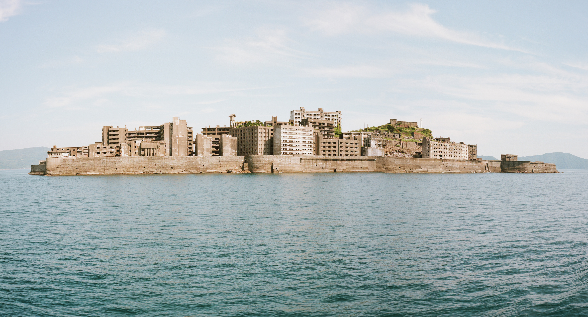 Op zo'n vijftien kilometer van Nagasaki rijst een kaal, betonnen eilandje op uit de woeste zee: Hashima, door de lokale bevolking in Japan ook wel Gunkanjima ('slagschipeiland') genoemd. Eind negentiende eeuw ontdekte men hier rijke steenkoollagen onder de zeebodem, waarna het piepkleine rotsblok transformeerde tot de meest dichtbevolkte plek op aarde, volgepropt met torenhoge flatgebouwen.