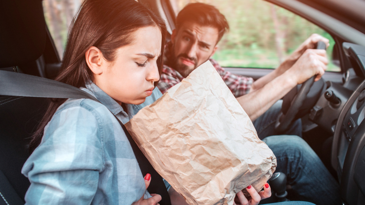 meisje houdt papieren zak vast en zit misselijk in een auto met wagenziekte