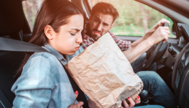 meisje houdt papieren zak vast en zit misselijk in een auto met wagenziekte