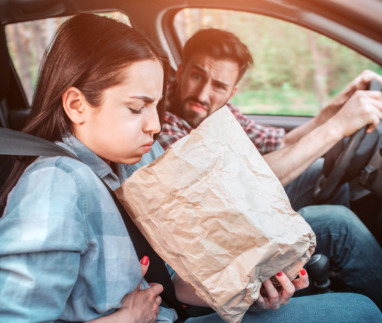 meisje houdt papieren zak vast en zit misselijk in een auto met wagenziekte