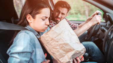 meisje houdt papieren zak vast en zit misselijk in een auto met wagenziekte
