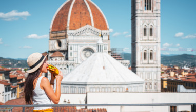 Jonge vrouw eet broodje met de kathedraal van Florence op de achtergrond