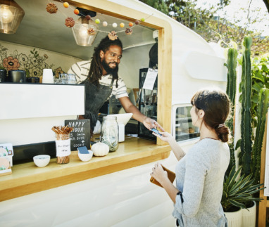 Food truck eigenaar neemt glimlachend creditcard van klant aan