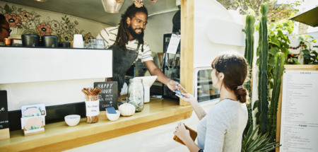 Food truck eigenaar neemt glimlachend creditcard van klant aan