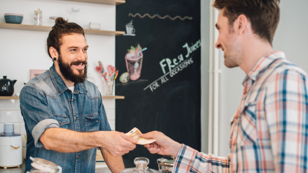 Ober neemt geld aan van klant in een cafe