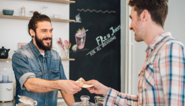 Ober neemt geld aan van klant in een cafe