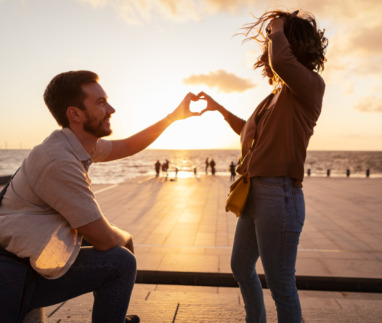 Man en vrouw maken met hun handen samen een hartje bij zonsondergang