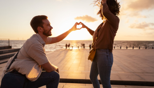 Man en vrouw maken met hun handen samen een hartje bij zonsondergang