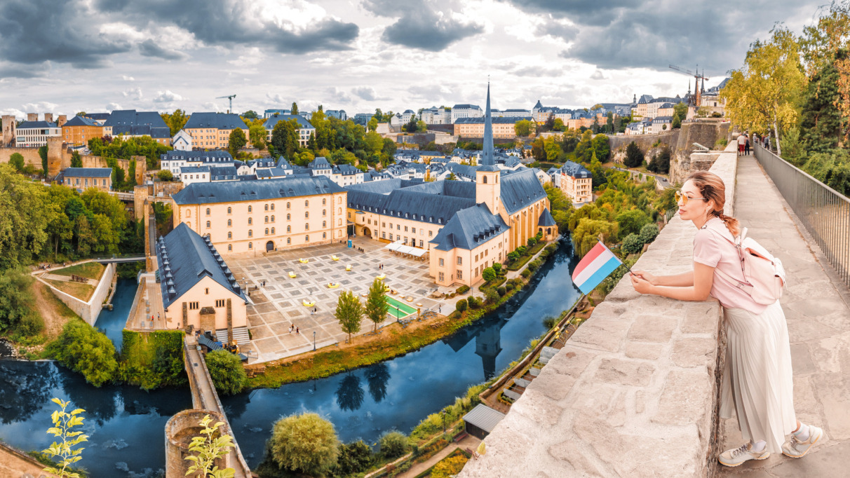 Vrouw geniet van het uitzicht over Luxemburg-stad met Luxemburgse vlag in de hand