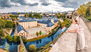 Vrouw geniet van het uitzicht over Luxemburg-stad met Luxemburgse vlag in de hand