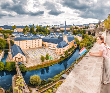 Vrouw geniet van het uitzicht over Luxemburg-stad met Luxemburgse vlag in de hand