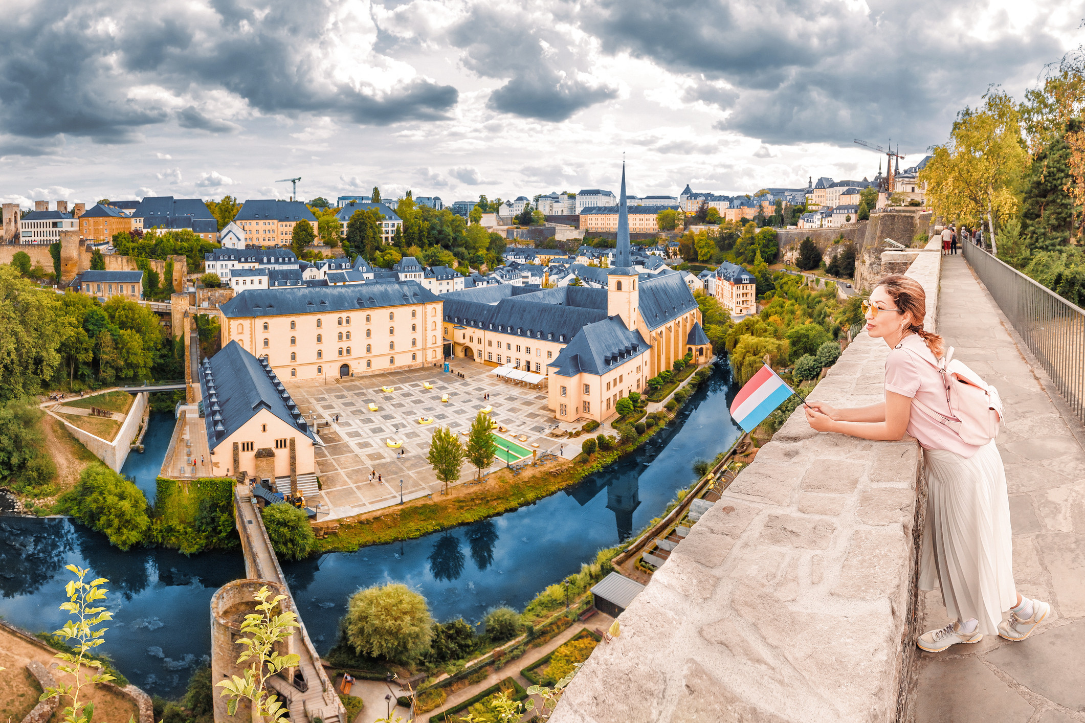 Vrouw geniet van het uitzicht over Luxemburg-stad met Luxemburgse vlag in de hand