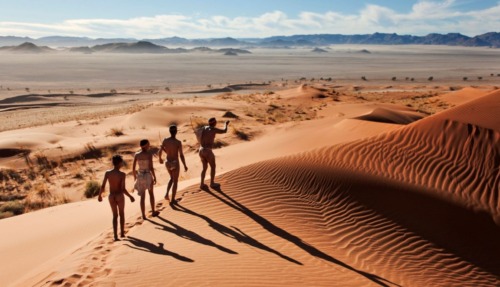 Traditionele jagers lopen door de rode zandduinen van de Namib-woestijn in Namibië