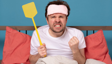 man holding a fly swatter wanting to kill annoying mosquito