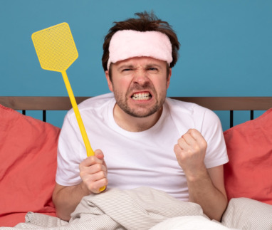 man holding a fly swatter wanting to kill annoying mosquito