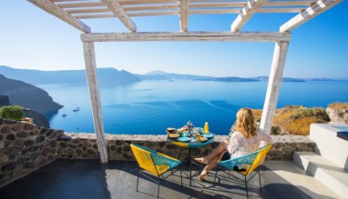 Woman enjoying breakfast with beautiful view over Santorini