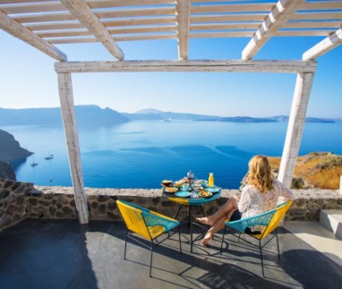 Woman enjoying breakfast with beautiful view over Santorini