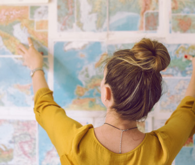 Vrouw plant haar reis met kaarten aan de muur