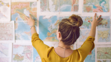 Vrouw plant haar reis met kaarten aan de muur