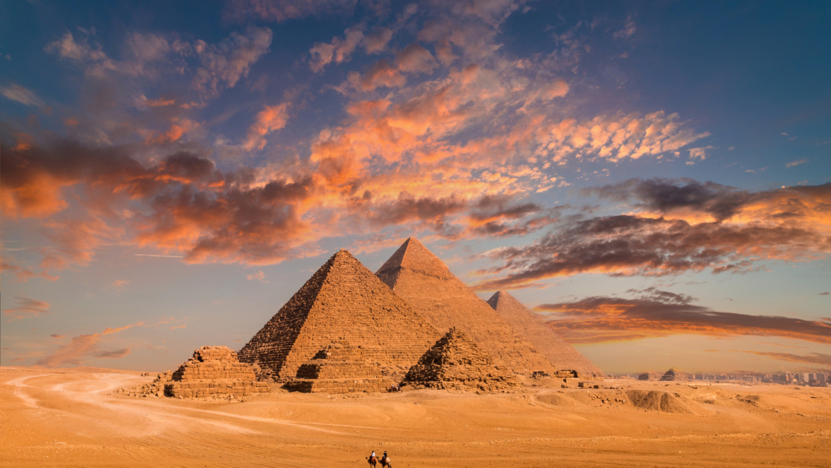 Piramides van Cheops in Gizeh, Egypte met kamelen op de voorgrond en dramatische luchten