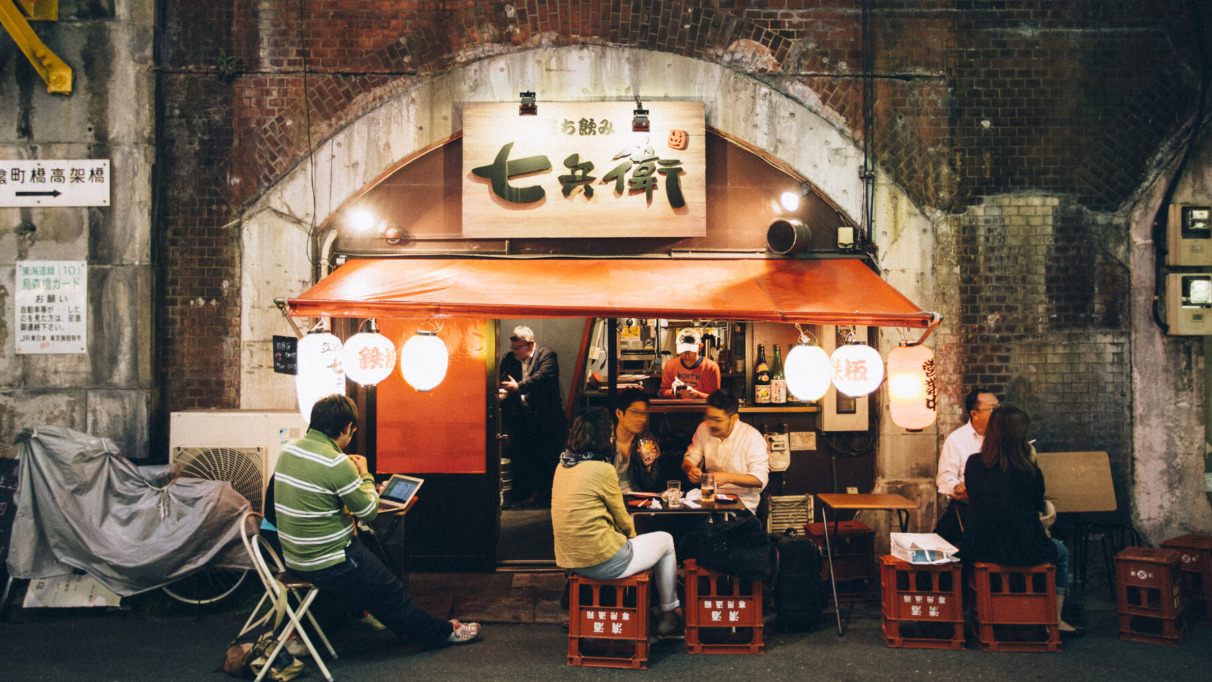 Gezellige Japanse eetkraam onder een spoorbrug n Shinbashi district in Tokio met lokale gasten