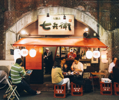 Gezellige Japanse eetkraam onder een spoorbrug n Shinbashi district in Tokio met lokale gasten