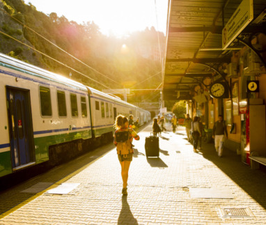 Reiziger met rugzak loopt over een perron richting een trein bij zonsondergang