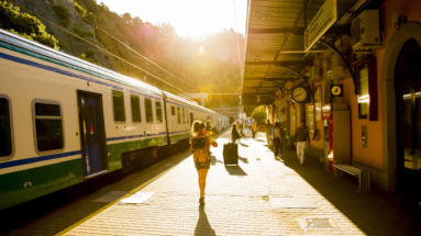 Reiziger met rugzak loopt over een perron richting een trein bij zonsondergang