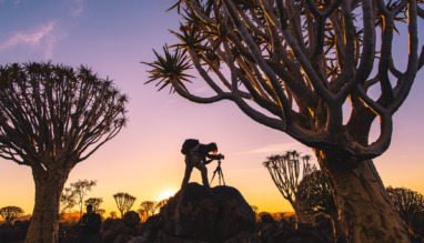 Reisfotograaf met statief legt een landschap vast bij zonsondergang