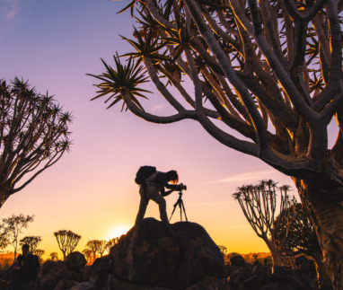 Reisfotograaf met statief legt een landschap vast bij zonsondergang