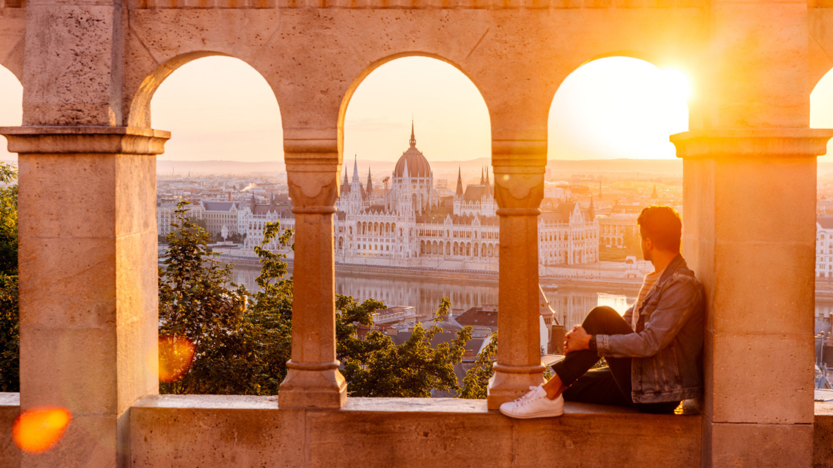 Man geniet van het uitzicht op het Hongaarse parlement in Boedapest bij zonsondergang, gezien door stenen bogen.