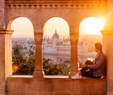Man geniet van het uitzicht op het Hongaarse parlement in Boedapest bij zonsondergang, gezien door stenen bogen.