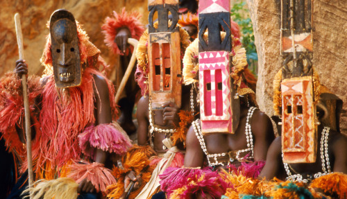 Dogon-mannen in kleurrijke kostuums en houten maskers tijdens een traditionele ceremonie in Mali.