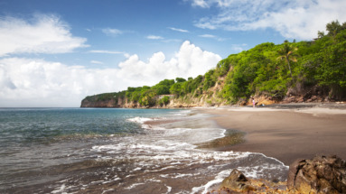 Het rustige zwarte zandstrand Woodlands beach omringd door groene kliffen op Montserrat.