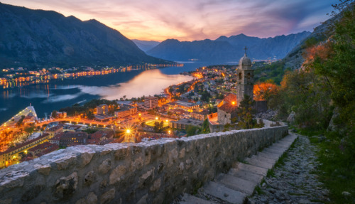 Adembenemend uitzicht op de Baai van Kotor in Montenegro bij zonsondergang, met bergen, sfeervolle verlichting en historische architectuur.