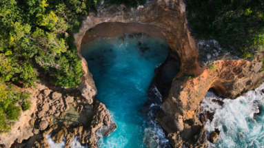 Luchtfoto van de afgelegen natuurlijke poel Anse Castalia omgeven door kliffen en weelderige vegetatie op Anse Bertrand, Guadeloupe.