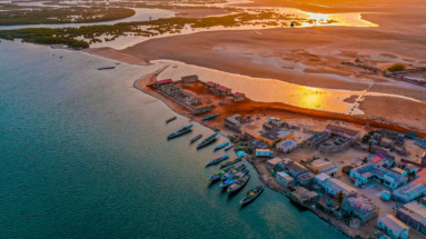 Ndangane aan de kust van Senegal bij zonsondergang, met kleurrijke boten en uitgestrekte waterwegen.