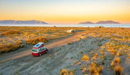 Camper in een uitgestrekt landschap bij zonsondergang in Albanië, omringd door grasvlaktes en bergen