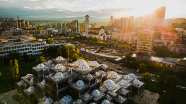 Uitzicht op Pristina bij zonsondergang, met de Nationale Bibliotheek van Kosovo en moderne stadsarchitectuur