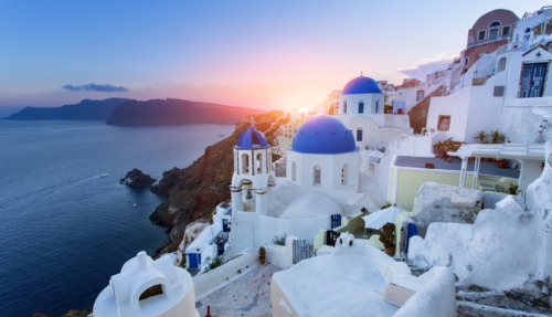 Griekenland: Iconische witte gebouwen met blauwe koepels, adembenemend uitzicht op de Egeïsche Zee bij zonsondergang