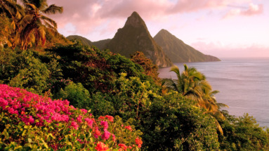 Uitzicht op de Pitons, twee iconische bergen op Saint Lucia, omgeven door tropisch groen en kleurrijke bloemen.