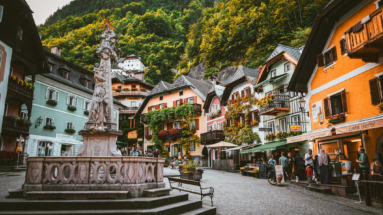 Het pittoreske dorpsplein van Hallstatt in Oostenrijk, omgeven door kleurrijke huizen en weelderige groene bergen.