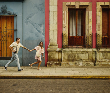 Man en vrouw rennen door de kleurrijke straten van Oaxaca, Mexico