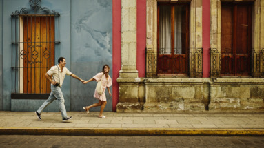 Man en vrouw rennen door de kleurrijke straten van Oaxaca, Mexico