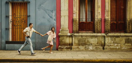 Man en vrouw rennen door de kleurrijke straten van Oaxaca, Mexico