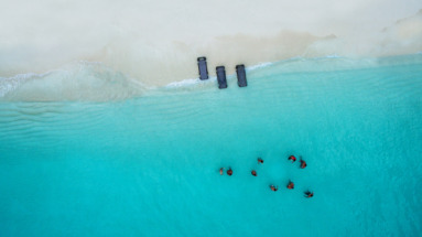 Luchtfoto van een wit zandstrand met ligbedden en mensen die zwemmen in het helderblauwe water op de Turks- en Caicoseilanden.